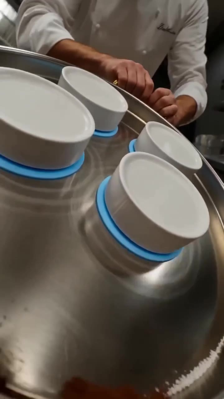 Chef tilting a silver tray while white dishes stay put on blue SlipSafe non-slip coasters